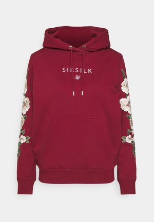 Burgundowa bluza z kapturem z przednią kieszenią, kwiatową haftem na rękawach, sznureczkami i białym logo "SikSilk" umieszczonym na środku klatki piersiowej.