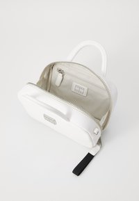 Borsa a zip bianca, con una superficie liscia, forma arrotondata, manico superiore e un interno beige con una piccola tasca con zip.