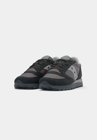 Pantofi sport dintr-un amestec de sueded negru și gri, cu plasă, talpă din cauciuc texturată și detalii distinctive ale logo-ului pe lateral.
