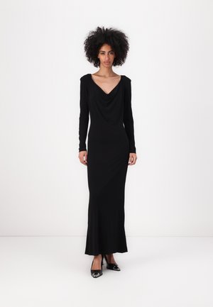 Black long-sleeve dress with a draped cowl neckline and form-fitting silhouette, made of a smooth fabric, paired with black pointed-toe heels.
