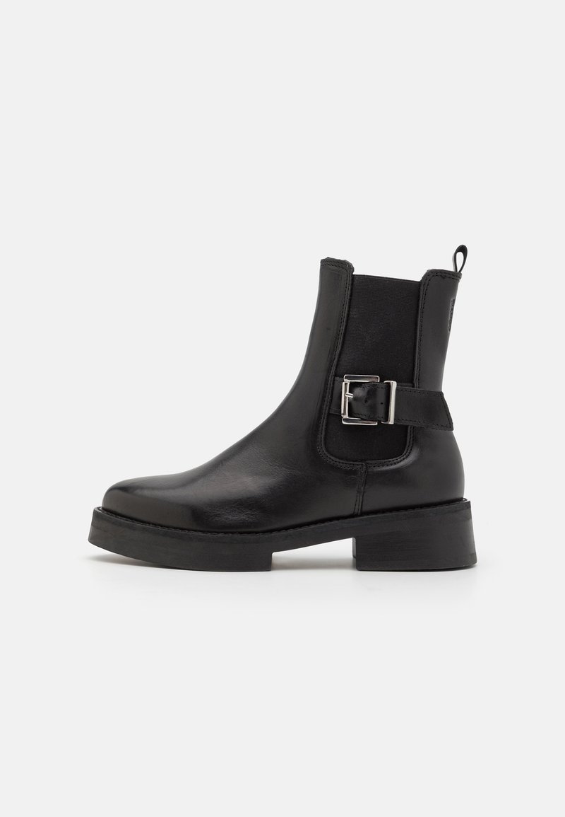 Bottines noires en cuir avec un bout rond, des panneaux élastiques sur les côtés, un accent de boucle et un petit talon épais. Texture lisse et semelle robuste.