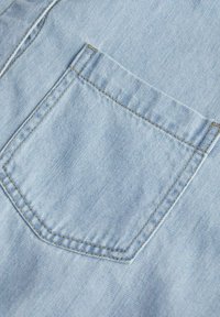 Tessuto di denim blu chiaro con una singola tasca a toppa angolata, cuciture dorate e una texture liscia.
