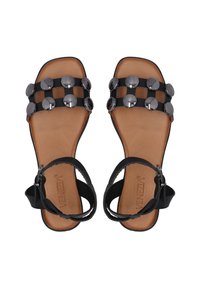 Zwarte platte sandalen hebben een gladleren zool, een raster van zwarte banden en metalen ronde accenten op de bovenkant. Inclusief verstelbare enkelband.