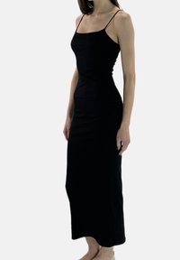 Czarna, dopasowana sukienka na cienkich ramiączkach, długość do połowy łydki, gładka faktura, prosty fason, bez widocznych wzorów ani zdobień.