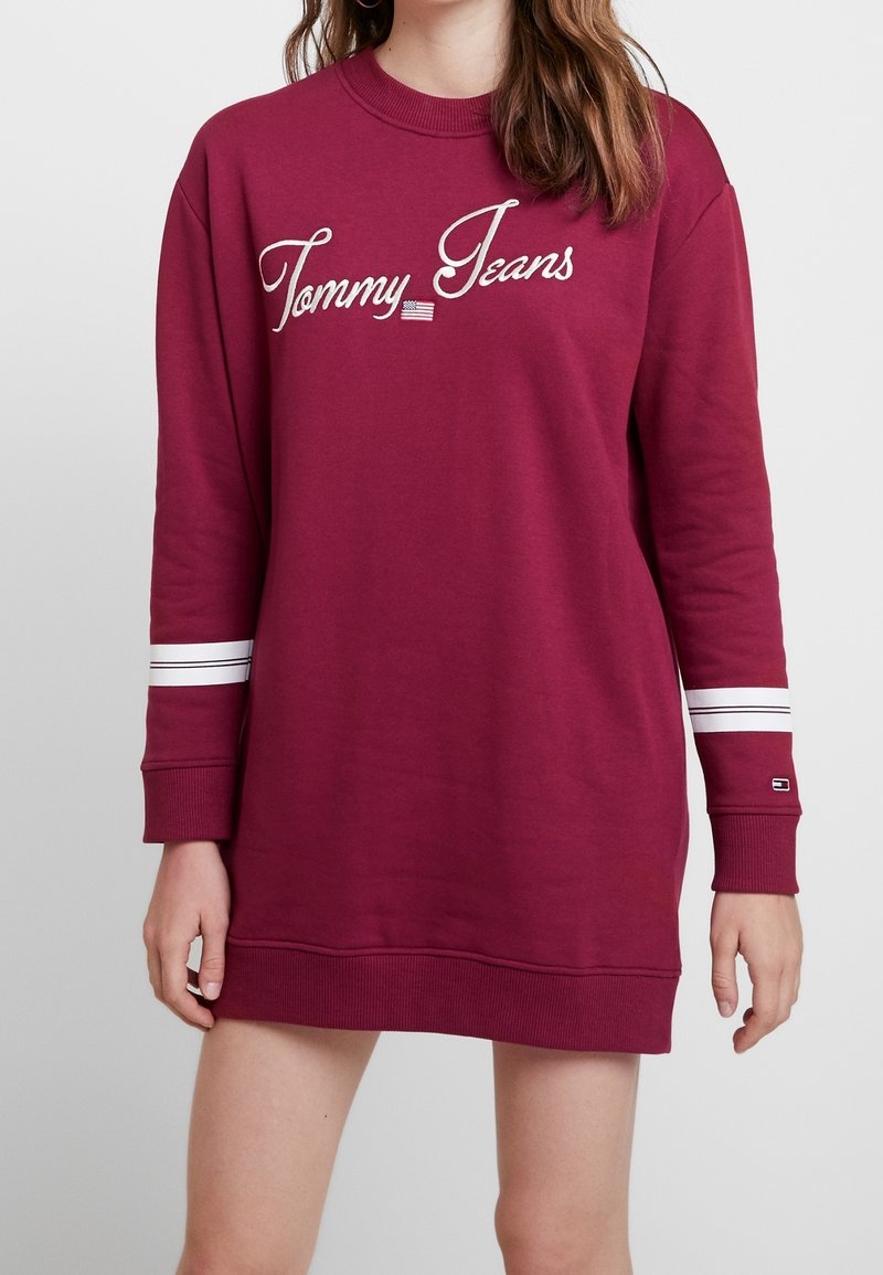 Bordeaux-huppari mekko pitkillä hihoilla, ribbireunuksilla, valkoisilla raidoilla hihoissa ja "Tommy Jeans" -logo kauniilla käsialalla rinnassa.