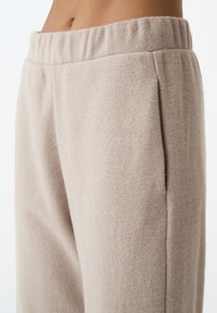 Lichtbeige fleece sweatpants met een elastische tailleband, zijzakken en een zachte, gestructureerde stof. Geen zichtbare patronen of hardware.