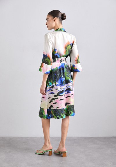 Šaty s květinovým potiskem z lehké tkaniny, s páskem v pase, zvonovými rukávy a barevným krajinným vzorem v zelených, modrých a růžových odstínech.