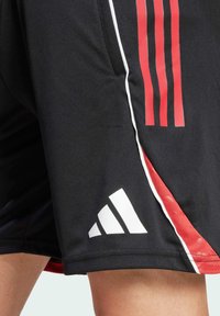 Schwarze Sportshorts mit roten Streifen an den Seiten, weißem Adidas-Logo am Saum, aus glattem Stoff gefertigt und mit einem elastischen Bund ausgestattet.