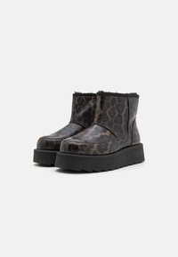 Botines de animal print de leopardo hechos de material texturizado, con una suela de plataforma negra resistente y un interior suave similar a la piel.