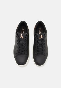 Svarta sneakers med en slät läderstruktur, rund tå, snörning och vit gummisula. Har subtila rosa accenter på hälen.