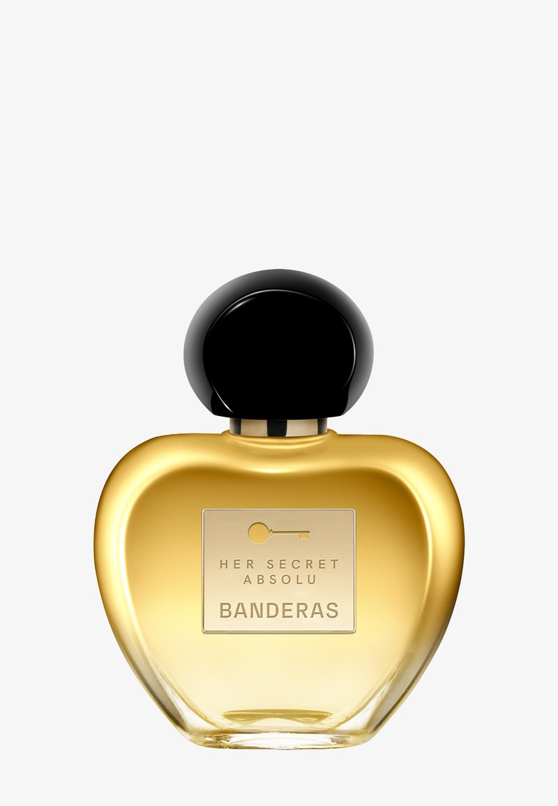 Gylden hjerteformet parfume flaske med sort rund hætte, mærket "Her Secret Absolu Banderas" med nøgleikon.