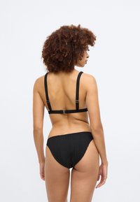 Μαύρο ριπ μπιикиνι με κλασικό τοπ bralette και ρυθμιζόμενους ιμάντες, συνοδευόμενο από αντίστοιχο χαμηλοκάβαλο σλιπ.