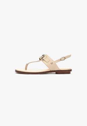 Sandalias planas beige con bucle para los dedos, una correa ajustable en el tobillo y un acento de hebilla en tono dorado. Parte superior de cuero suave y suela plana.