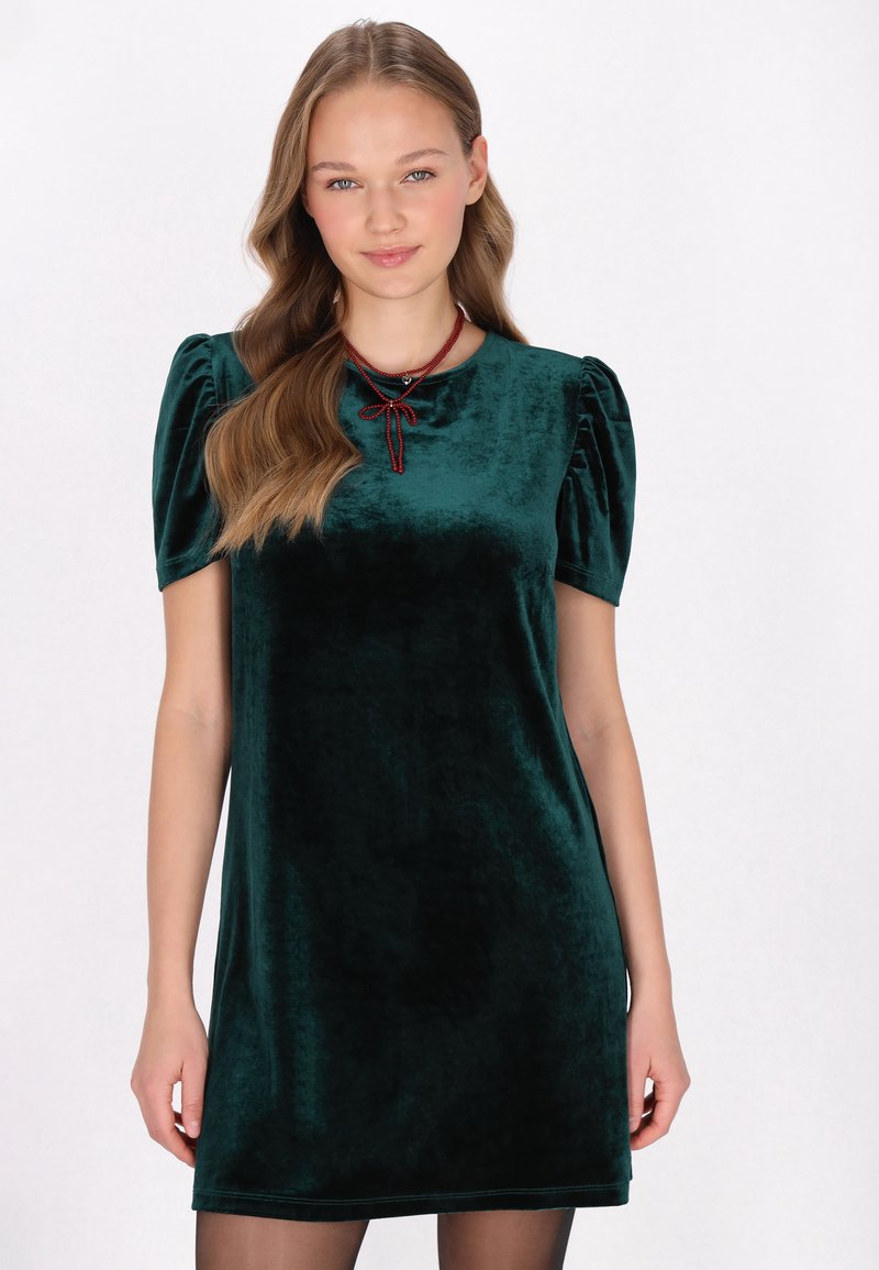 Smaragdgrünes Samtkleid mit kurzen Puffärmeln und rundem Halsausschnitt, das über einen dezenten Glanz und ein gebundenes Detail am Hals verfügt.
