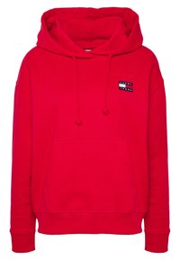 Czerwona bluza z kapturem, z trokami i kieszenią z przodu. Posiada naszywkę z logo "TOMMY JEANS". Wykonana z miękkiego materiału z prążkowanymi mankietami i dołem.