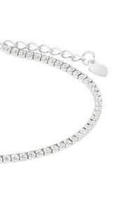 Pulsera de tenis de plata con piedras preciosas redondas claras y una cadena ajustable que termina en un pequeño charm en forma de corazón sobre un fondo blanco.