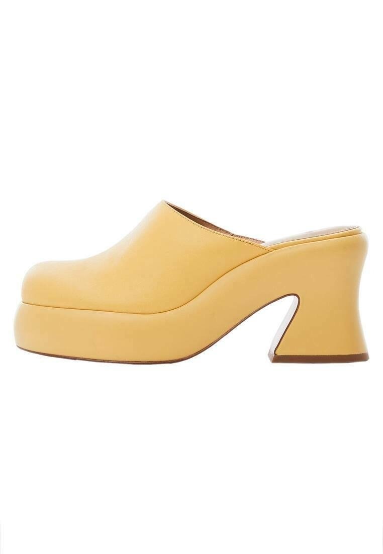 Mule en cuir jaune avec une épaisse semelle plateforme et un talon bloc à la forme unique.