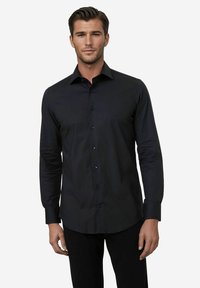 Zwarte, langemouwen overhemd met knopen en een puntige kraag, met een gladde textuur en bijpassende knopen, gestopt in donkere broeken.