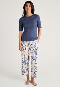 Twee-delige loungewear set: marineblauw top met korte mouwen in een soepele stof, gecombineerd met witte broek met blauwe en gouden botanische patronen.