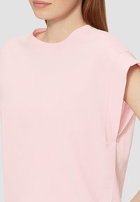Růžové triko s krátkým rukávem a kulatým výstřihem, se zahnou rukávy a jemnou, hladkou látkou. Jednoduchý design bez vzorů nebo akcentů.
