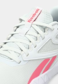 Pantofii sport albi cu un superior din plasă, având accente roz și un logo Reebok pe limba pantofului. Detalii din țesătură texturată și talpă din cauciuc vizibile.