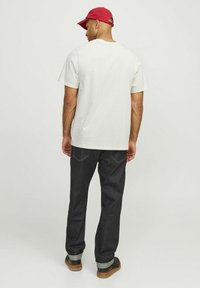 White short-sleeve T-shirt, dark denim jeans, red cap. T-shirt has a classic crew neck, jeans feature contrasting stitching and rolled cuffs.