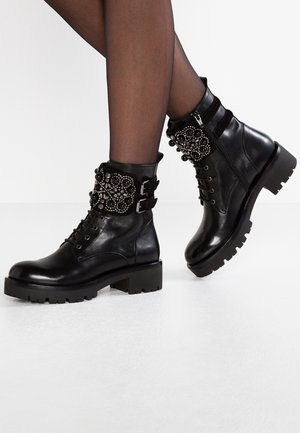 Schwarze Leder-Ankle-Boots mit einer stabilen Sohle, dekorativen Perlen- und Blumenelementen am Schaft sowie einem seitlichen Reißverschluss.
