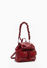 Rucksack aus rotem Leder mit einer gerafften Griffe, Frontklappe und zwei äußeren Taschen. Verfügt über einen Kordelzugverschluss und silberne Beschläge.