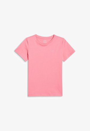 Jeune fille debout, portant un sweat à capuche bleu clair zippé, un t-shirt rose, des leggings bleus, des chaussettes blanches et des baskets blanches sur un fond uni.