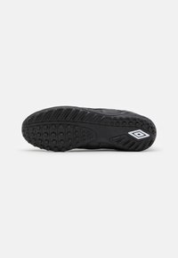 Black athletic shoe sole with textured rubber, featuring raised circular grips and a logo detail. Flat profile and defined tread pattern.