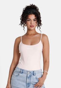 Ljusrosa bodysuit med tunna stammar och rundad halsringning, med logotyp framtill. Matcher med högmidjade ljusblå denimshorts.