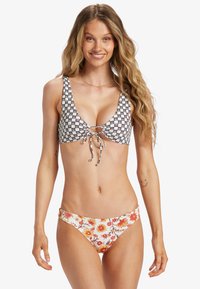 Čierny a biely vzorovaný bikiny top s viazaním vpredu; krajkové bikiny nohavičky v odtieňoch oranžovej a žltej; hladká textúra látky.