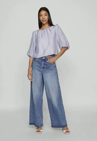 Lavender cropped blouse with puff sleeves paired with high-waisted wide-leg light blue denim jeans. The outfit features a casual, relaxed fit.