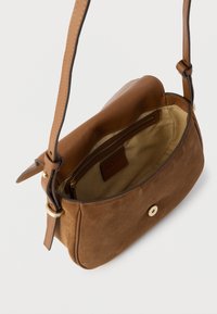 Καφέ τσάντα χειρός από σουέντ με δομημένο σώμα, δερμάτινο λουρί και μαγνητικό κλείσιμο. Το εσωτερικό διαθέτει θήκη με φερμουάρ και ταμπά επένδυση.