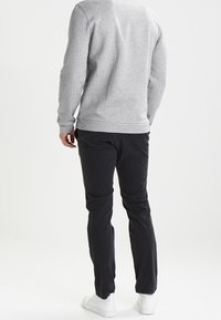 Sudadera gris con un acabado texturizado, combinada con pantalones negros y zapatillas blancas. El conjunto presenta un ajuste casual y relajado.