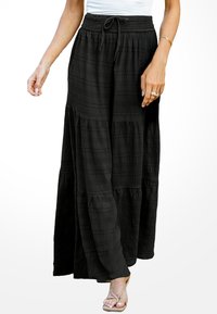 Zwarte maxi rok met een gelaagd ontwerp, uitgevoerd in een gestructureerde stof, met een elastische tailleband en details van een trekkoord. Vloeiende silhouet.
