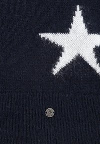 Maglione lavorato a maglia blu navy con un grande disegno di stella bianca e un piccolo etichetta metallica con "by Ling" sul bordo inferiore.