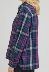 Bomullsfritidsskjorta med en rutigt mönster i marinblått, rosa och grått. Krage med knappar, långa ärmar och en bröstficka.