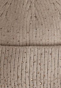 Beanie beige lavorato a maglia con texture a coste verticali, impreziosito da perline marroni sparse. Materiale in lana morbido dall'aspetto caldo.