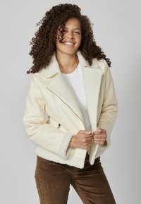 Krém színű műbőr dzseki, shearling gallérral és mandzsettával, cipzárral záródik, és a testen texturált minta található.