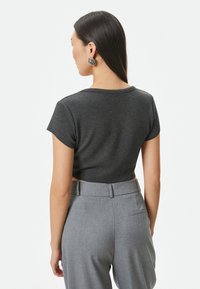 Mørkegrå cropped t-shirt med korte ærmer, lavet af blødt stof. Sammen med grå skræddersyede bukser med en sidelomme og pæne pressede folder.