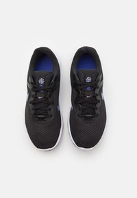 Chaussures de sport noires avec une tige en mesh, une doublure intérieure bleue et une semelle blanche. Elles comportent des lacets noirs et des accents de logo bleus.