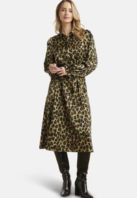 Vestito con stampa leopardata, collo con risvolto, maniche lunghe e vita con cintura. Realizzato in materiale setoso, presenta motivi neri e beige.