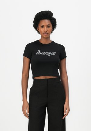 Black cropped t-shirt made of cotton, featuring a silver logo design "hugo" across the chest. Round neckline and short sleeves.