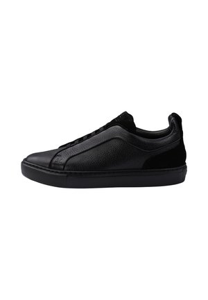 Sneaker nera low-top con tomaia in pelle liscia e testurizzata, chiusura con lacci e suola piatta in gomma, orientata verso sinistra su sfondo bianco.