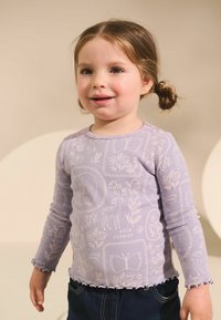 Fialová košile s dlouhým rukávem a texturovaným designem, která obsahuje obrysové vzory zvířat a květin; klikatý lem v pase a na manžetách.