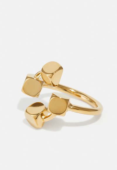 Bague en or présentant trois formes cubiques abstraites avec des surfaces lisses et réfléchissantes. La bande est fine et arrondie, renforçant le design moderne.