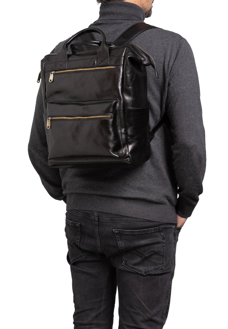 Sac à dos en cuir noir avec une texture lisse, deux poches zippées à l'avant et une poignée supérieure. Bandoulières réglables pour un transport pratique.