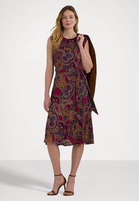 Hihaton, polven pituinen mekko paisley-kuvioilla, joissa on viininpunaista, sinistä ja kultaa. Mukana vyöllä varustettu vyötärö. Yhdistetty ruskeisiin korkokenkiin.