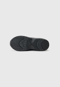 Black shoe sole with a textured rubber design, featuring distinct treads and patterns for traction. Embossed logo detail present.